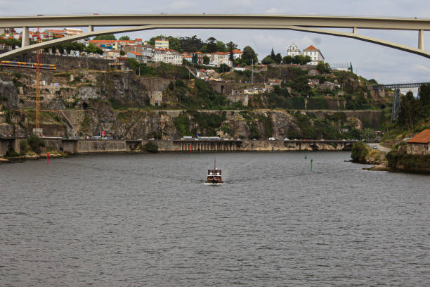 Scenic view of a vintage wooden boat anchored near Douro riverfront city architecture under a clear sky. Porto City, Portugal
