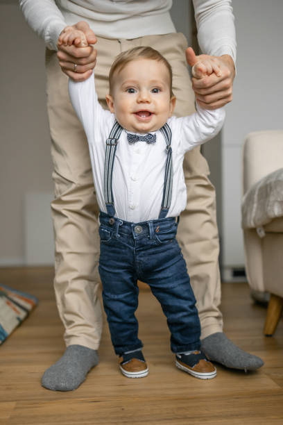 istock Adorable Baby Boy Learning to Walk with Parent's Help 2166247070