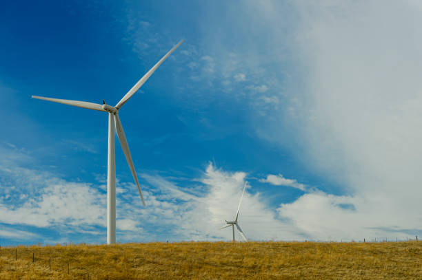 Wind Turbines lined up along a coastal wind turbine farm, with clouds in background.