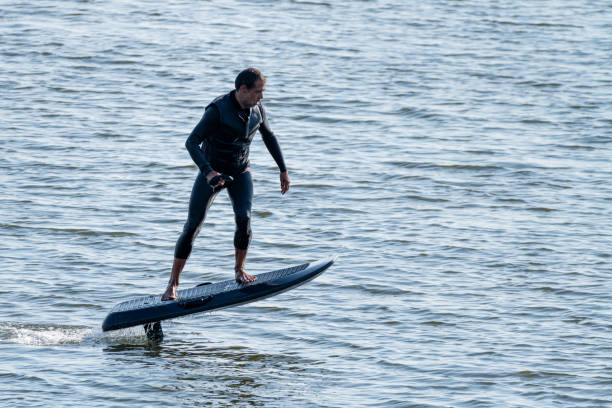 istock Man riding electric hydrofoil surfboard over rippling water 2166249417