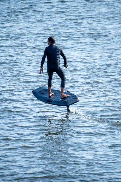 istock Surfer rides electric hydrofoil board above choppy water 2166249475