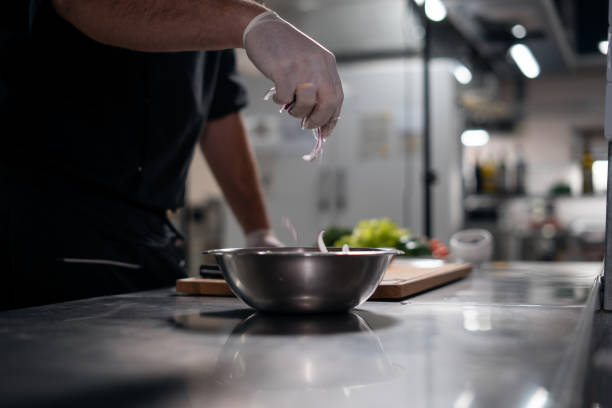 istock chef cook hands in gloves prepare salad and adding red onion in bowl at kitchen 2166254292
