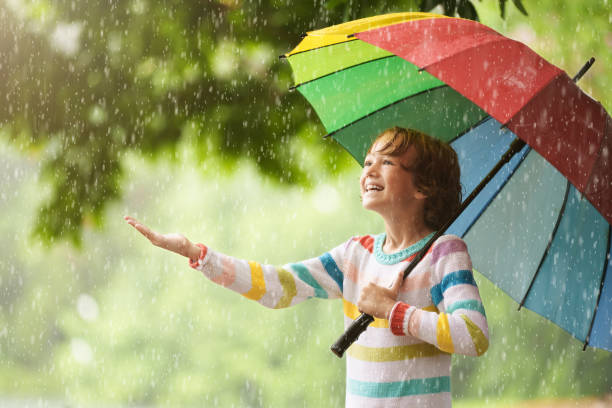 istock Child playing in rain. Kid jumping in puddle. 2166256268