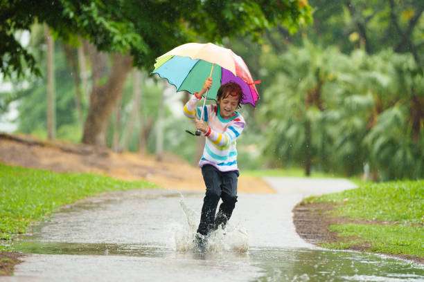 istock Child playing in rain. Kid jumping in puddle. 2166257225
