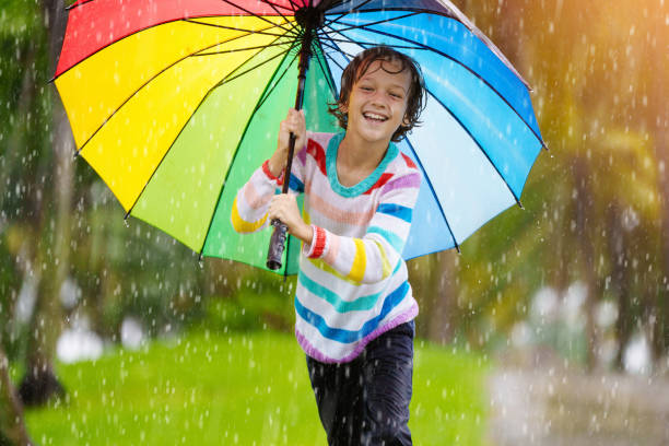 istock Child playing in rain. Kid jumping in puddle. 2166257370