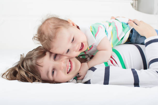 Two young children having fun holding paintbrushes to their heads