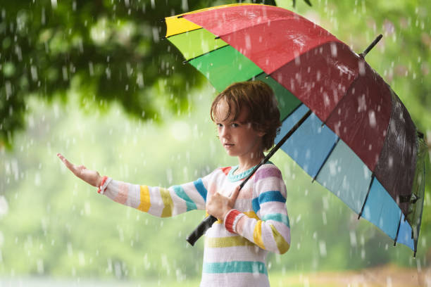istock Child playing in rain. Kid jumping in puddle. 2166257466
