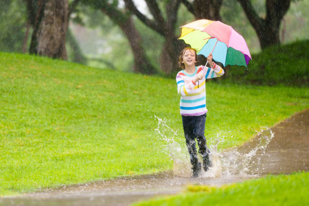 istock Child playing in rain. Kid jumping in puddle. 2166257491