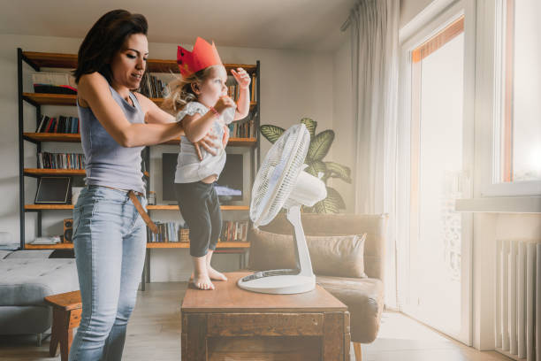 istock Mother lifting daughter having fun with fan on table 2166259318