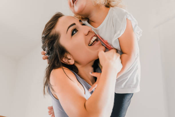 istock Young mother lifting laughing daughter having fun together 2166259579