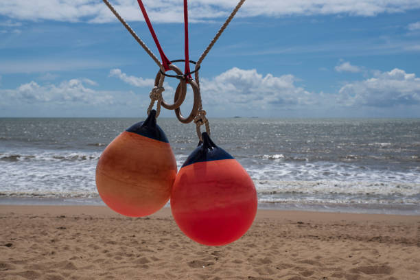 Red boat covers hanging from ropes with the beach and sea in the background