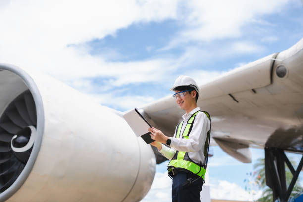 istock Male engineer in white hardhat standing and holding tablet working aircraft maintenance mechanics moving through hangar. 2166280529