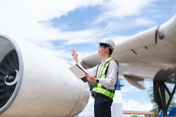 istock Male engineer in white hardhat standing and holding tablet working aircraft maintenance mechanics moving through hangar. 2166280542