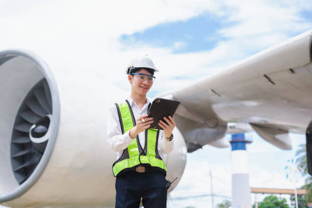 istock Male engineer in white hardhat standing and holding tablet working aircraft maintenance mechanics moving through hangar. 2166280545