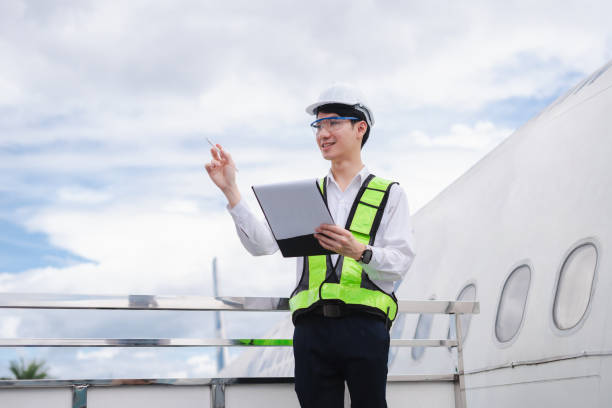 istock Male engineer in white hardhat standing and holding tablet working aircraft maintenance mechanics moving through hangar. 2166280549