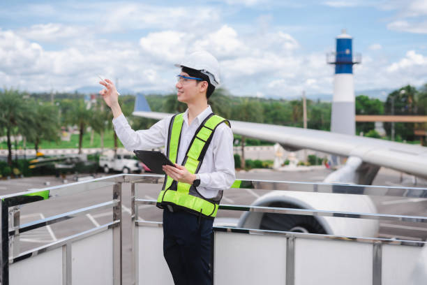 istock Male engineer in white hardhat standing and holding tablet working aircraft maintenance mechanics moving through hangar. 2166280563