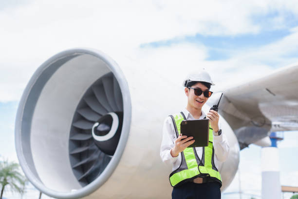 istock Male engineer in white hardhat standing and holding tablet working aircraft maintenance mechanics moving through hangar. 2166280572