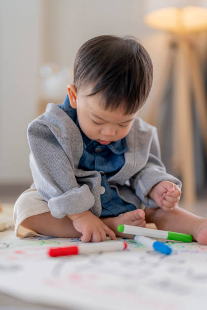 istock Relaxing Asian baby boy sit relax lying down and enjoy to using maker color drawing picture on drawing paper at home Little boy drawing on the floor 2166283854