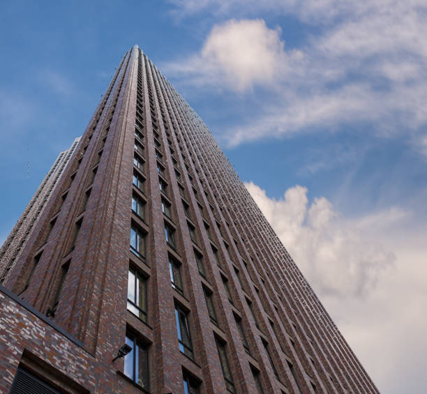 A tall building against a background of blue, cloudy sky. The building is very tall and has many windows.