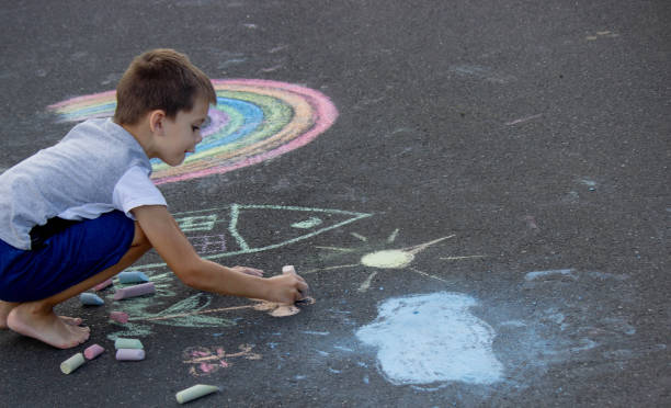 istock the boy draws with chalk on the asphalt. Selective focus 2166287956