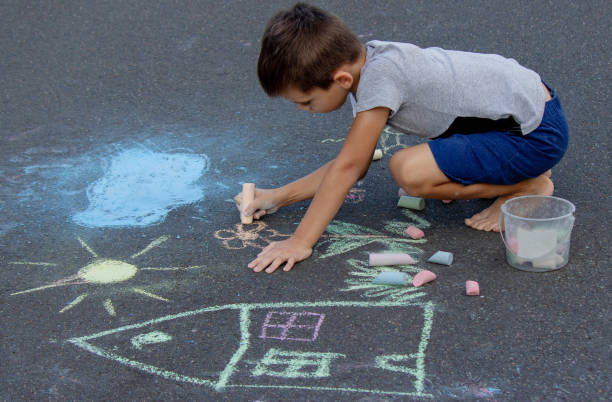 istock the boy draws with chalk on the asphalt. Selective focus 2166287958