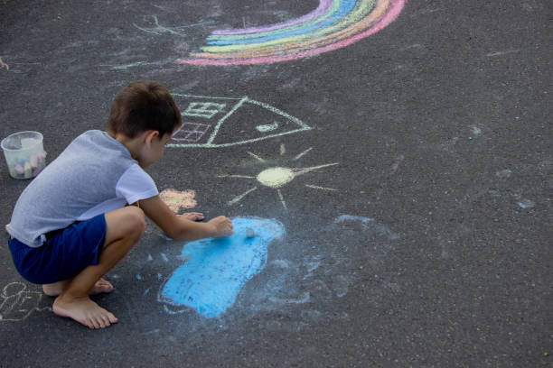 istock the boy draws with chalk on the asphalt. Selective focus 2166287959