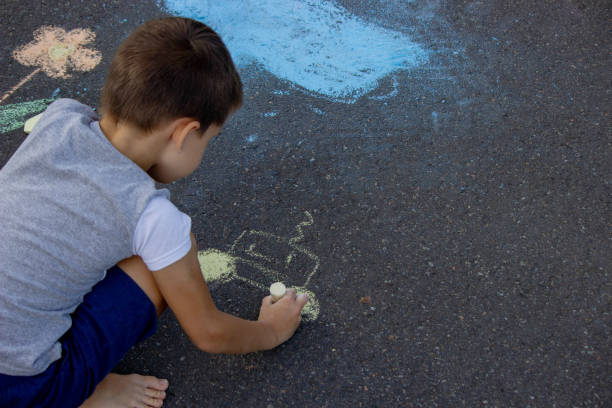 istock the boy draws with chalk on the asphalt. Selective focus 2166287972