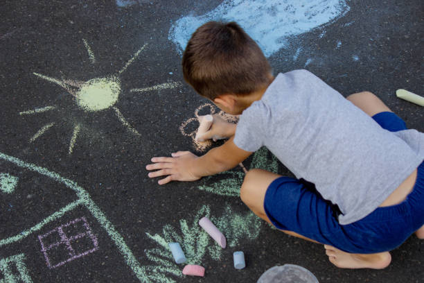 istock the boy draws with chalk on the asphalt. Selective focus 2166287975