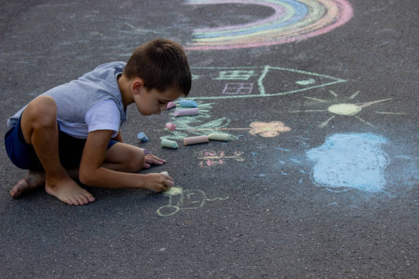 istock the boy draws with chalk on the asphalt. Selective focus 2166287976
