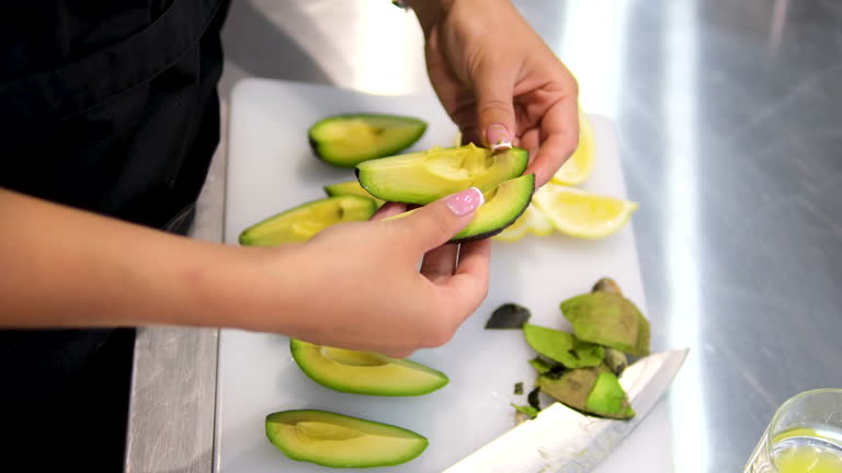 Peel the avocado Woman peeling Halved green avocado fruit while cooking at domestic kitchen