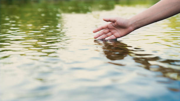 istock A female hand touching the river water 2166290164