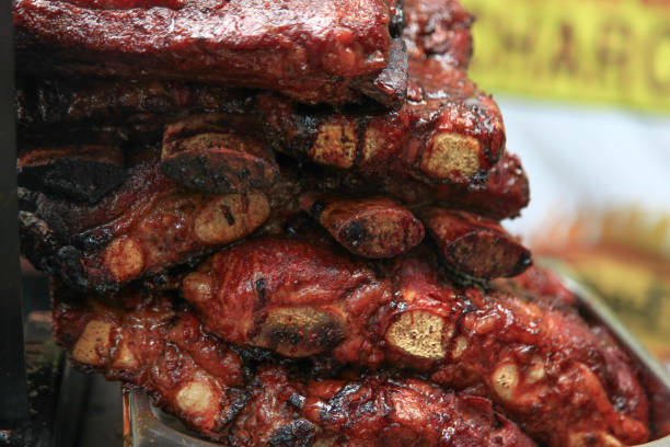 Delicious juicy grilled ribs with honey and mustard sauce with salt, spices and herbs on a dark concrete background