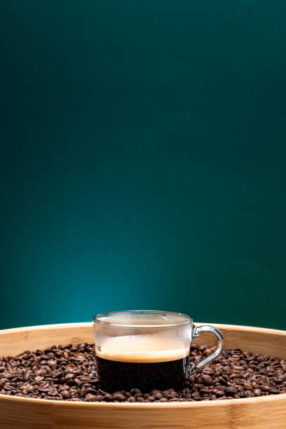 A coffee cup placed in a studio space with a pleasant green background, the cup sitting on coffee beans, details of the cup, details of the coffee beans captured with macro lenses, ideal for advertisements