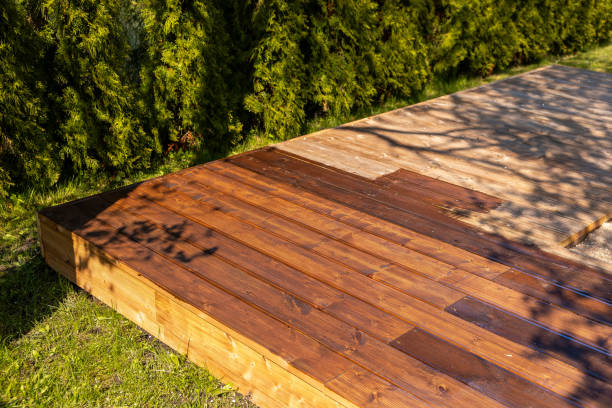 istock Partially stained wooden deck in a backyard with sunlight casting shadows 2166294402