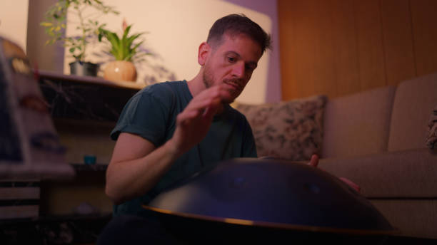istock Man sitting on ground and playing handpan 2166300151