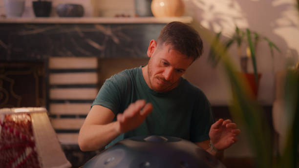 istock Man sitting on ground and playing handpan 2166300170