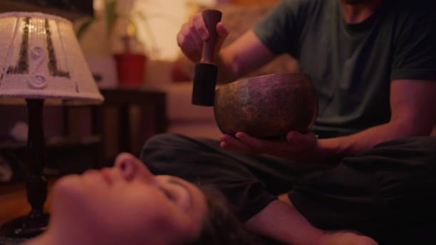 A man is using a Tibetan bowl for a music therapy session.