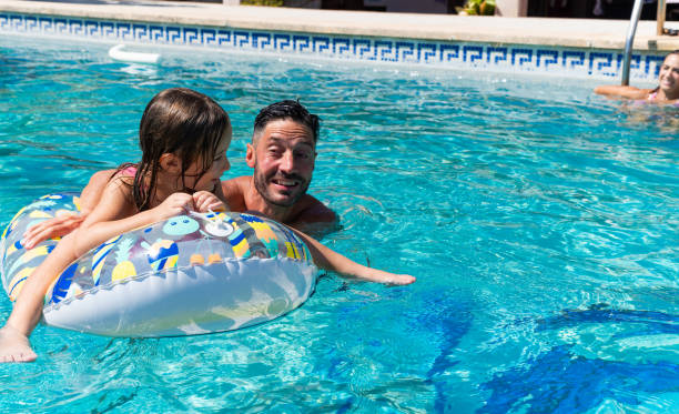 istock Father and daughter having fun, swimming in a pool on an inflatable ring 2166300227