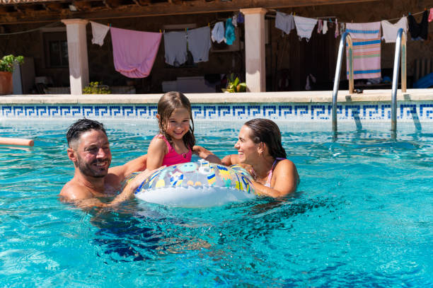 istock Happy family having fun, playing with inflatable ring in swimming pool 2166300241