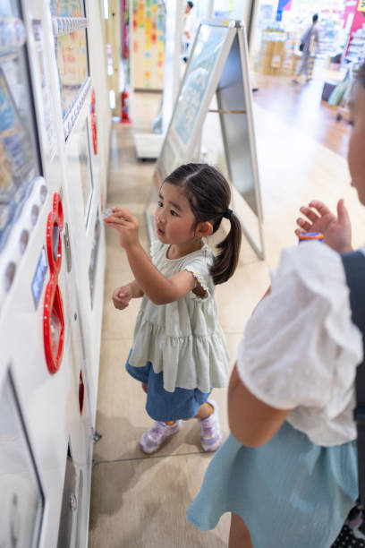 Little girl buying a bottle of drink using vending machine