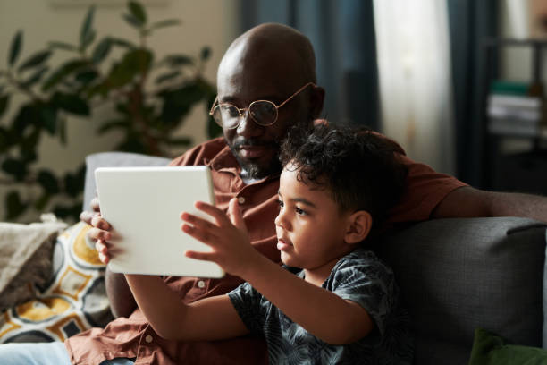 istock Boy watching online cartoons with father 2166305063