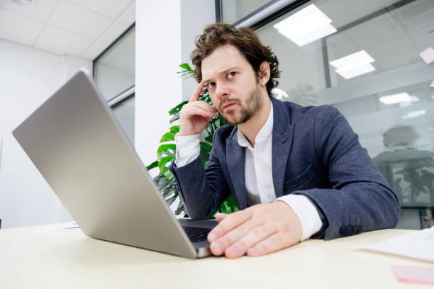 istock A young trader with a beard is focused on his laptop in a modern office. Ideal for showcasing finance and trading activities. 2166305266