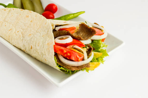 Traditional Turkish Kebab,Doner wrapped with flat bread,lavas on long plate at white surface