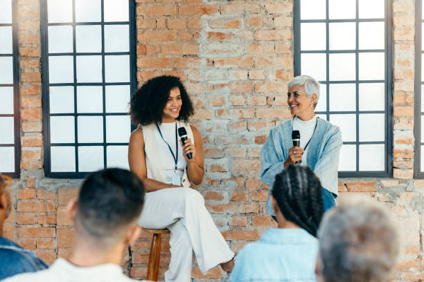 Women presenters discussing business with an audience in a casual setting. Female speakers giving discussing and giving talk to public