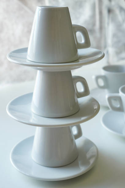 istock Stacked white coffee cups and saucers on a white table 2166309191