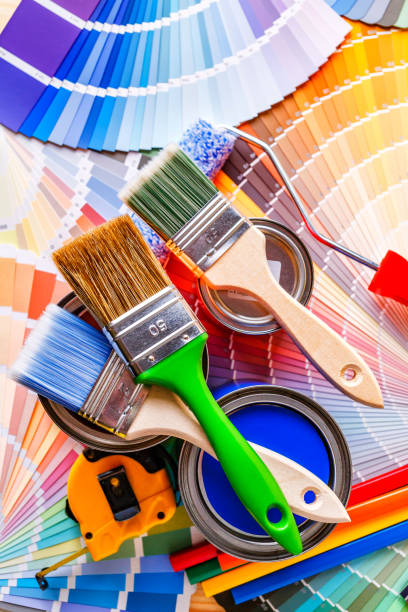 istock Painter and decorator work table with house project, color swatches, painting roller and paint brushes 2166311705