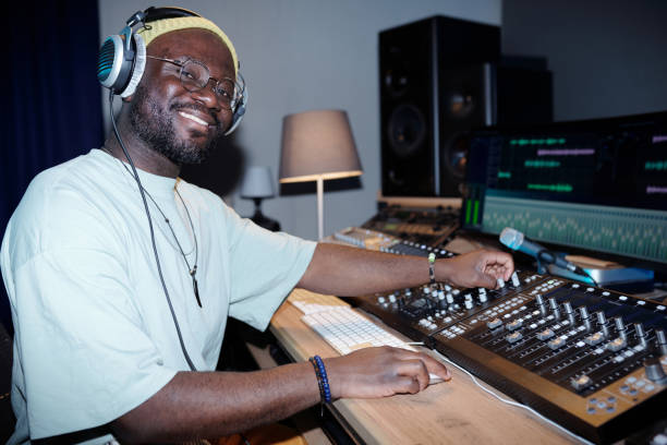 istock Smiling Man Operating Sound Mixing Equipment in Studio 2166312081