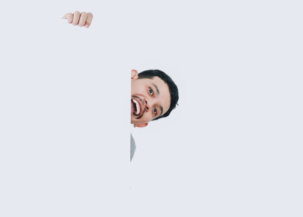 istock happy shocked expression of asian man looking to camera, peeking while holding banner blank signboard or copyspace for slogan 2166313056