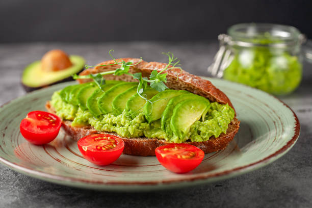 istock Vegan sandwich with avocado and tomatoes on a plate, on a gray background 2166316433