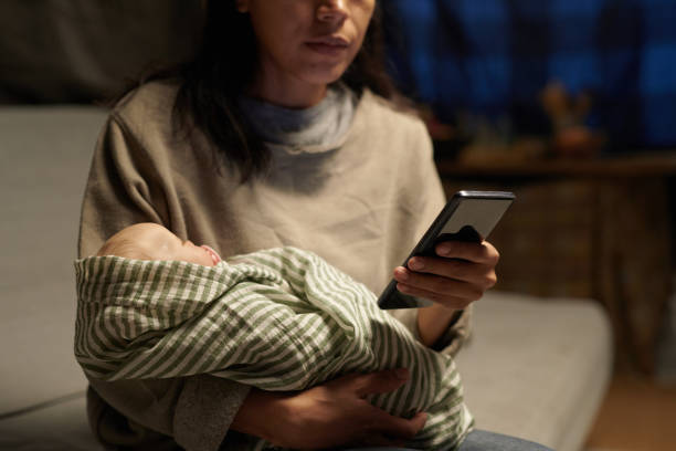Mother Holding Infant While Checking Smartphone